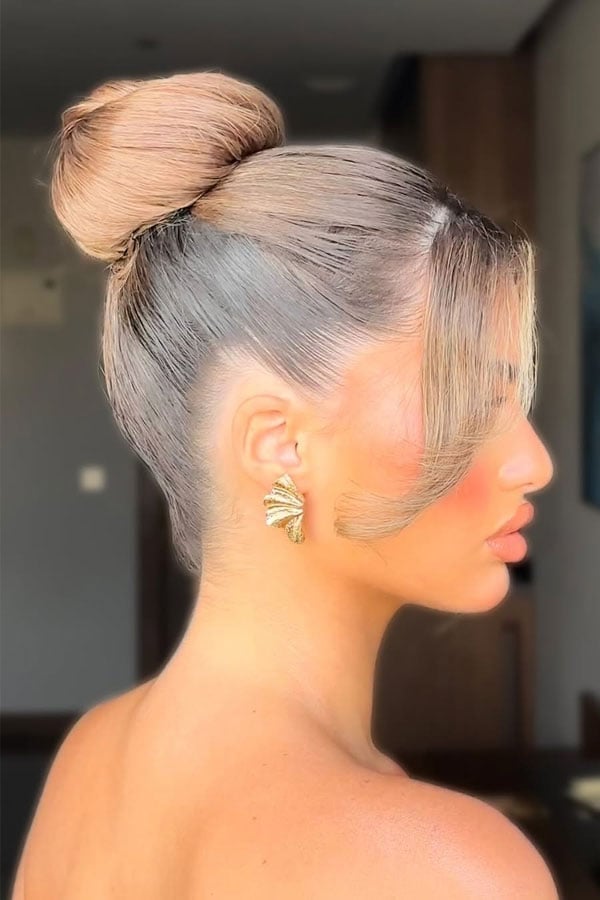 High Bun With Blonde Highlights and Curtain Bangs — Trendy High Bun Hairstyles