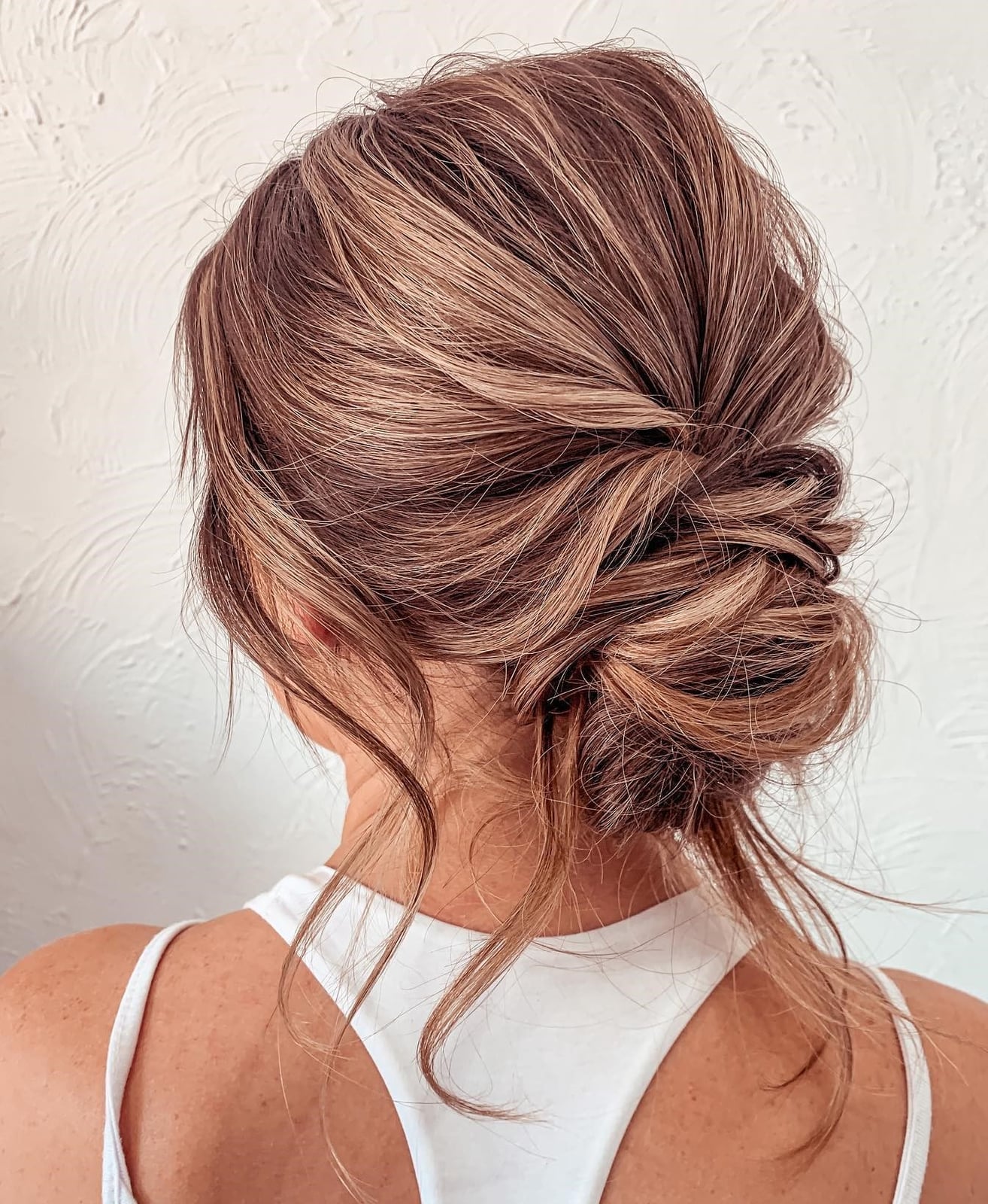 Long Warm Brown Balayage Textured Low Bun With Face-Framing Pieces Long Warm Brown Balayage Textured Low Bun With Face-Framing Pieces — Trendy Wedding Guest Updos