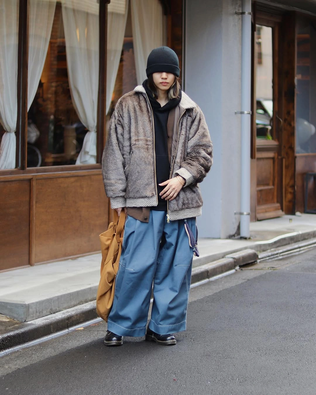 Taupe gray textured jacket, black hoodie, beanie and wide blue pants