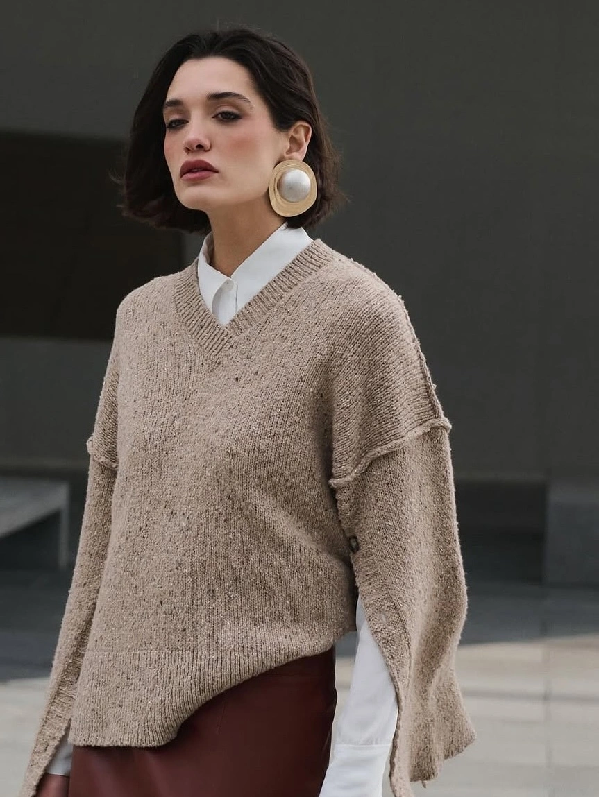 Beige V-neck sweater over white collared shirt with large cream earrings