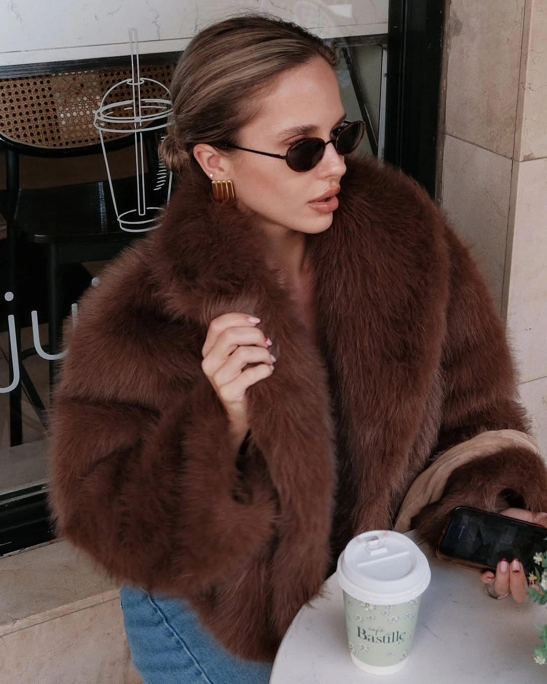 Cropped chocolate brown plush jacket, blue jeans and narrow sunglasses