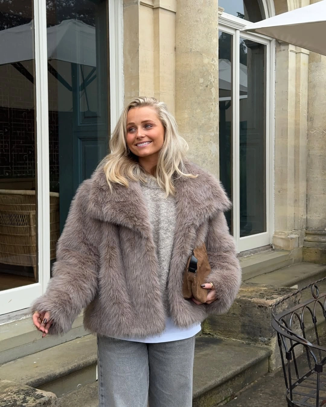 Cropped gray taupe plush jacket with gray jeans and brown handbag