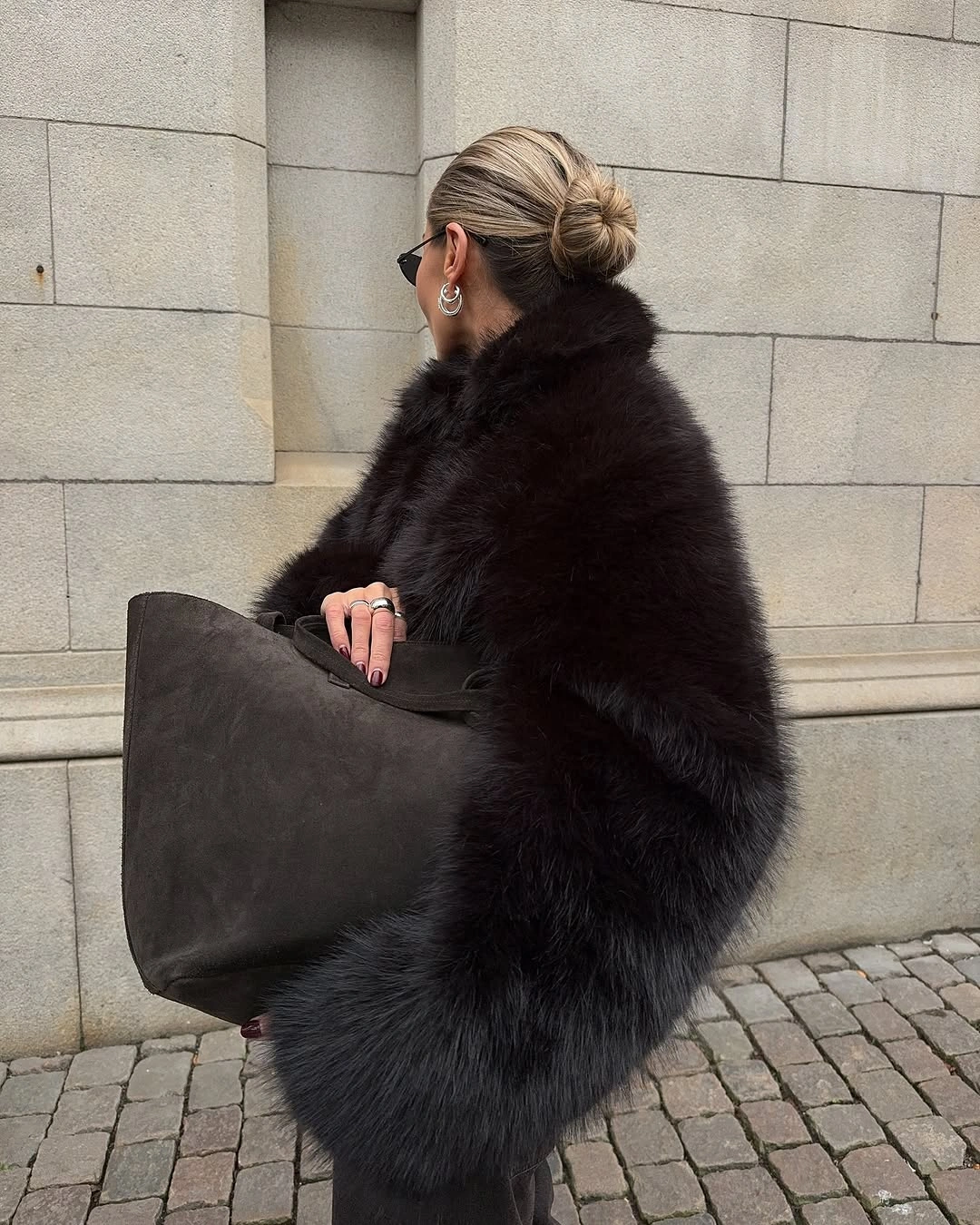 Full dark plush jacket with large charcoal tote and narrow sunglasses