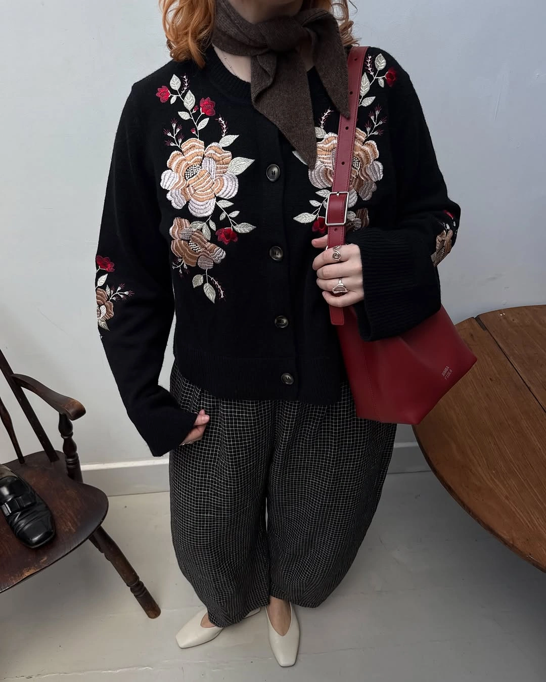 Black floral cardigan, brown scarf, cropped trousers, white flats, red bag
