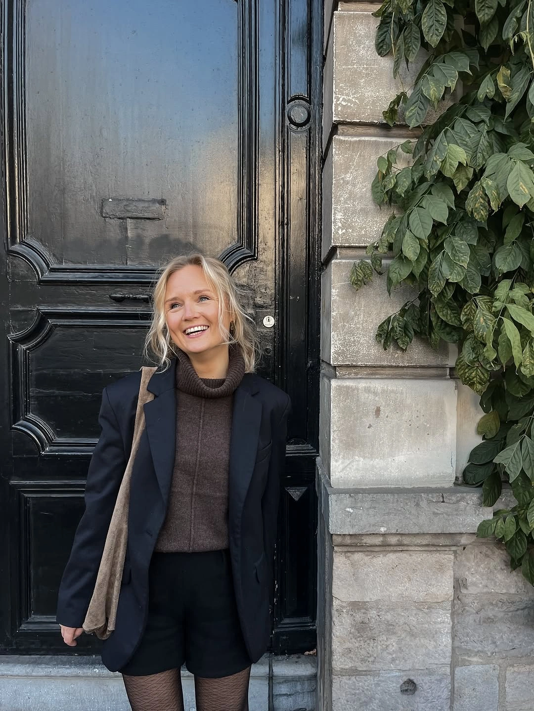 Dark blazer over brown turtleneck, black shorts, and patterned tights
