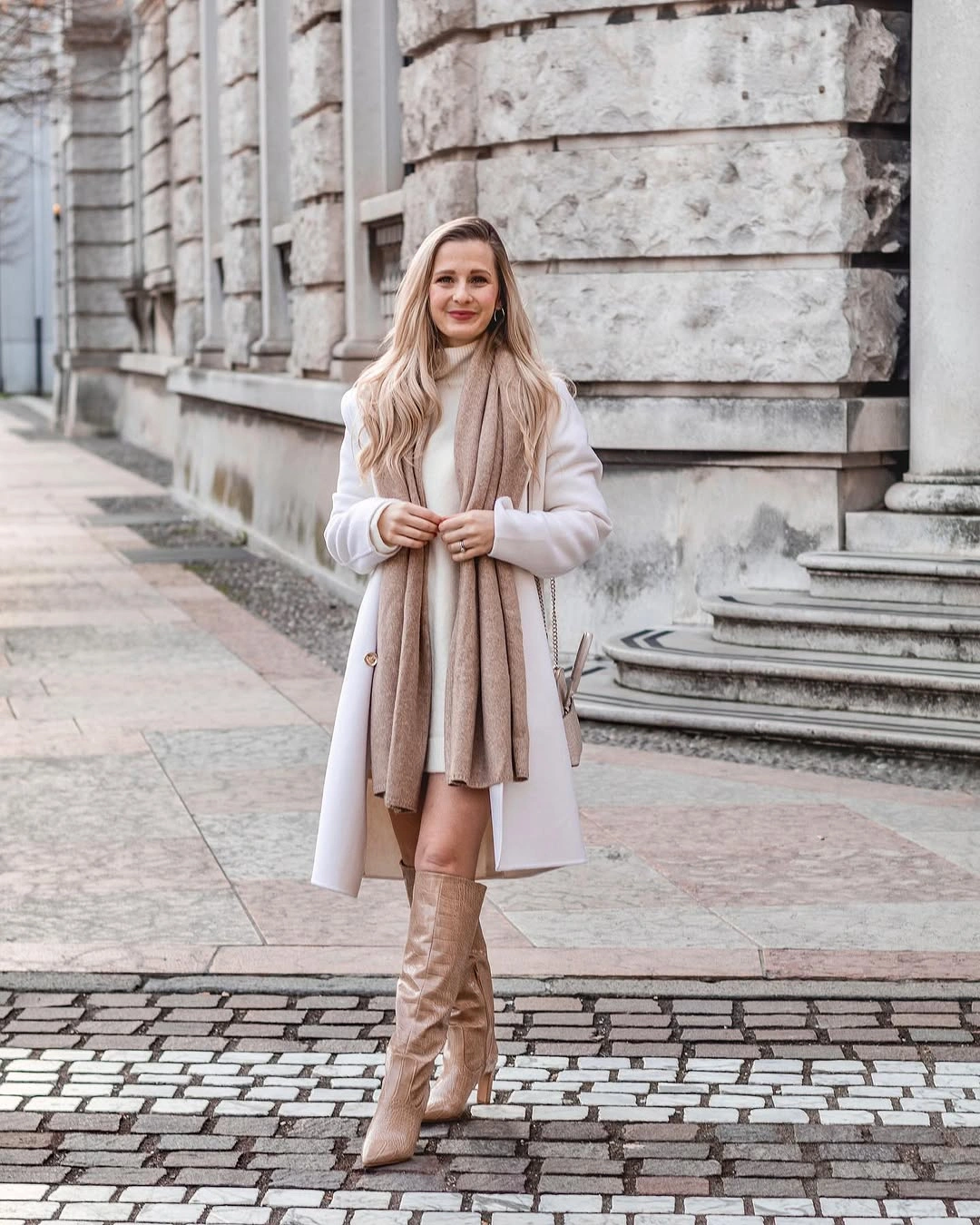 White coat, taupe scarf, short pale layer, and knee-high boots