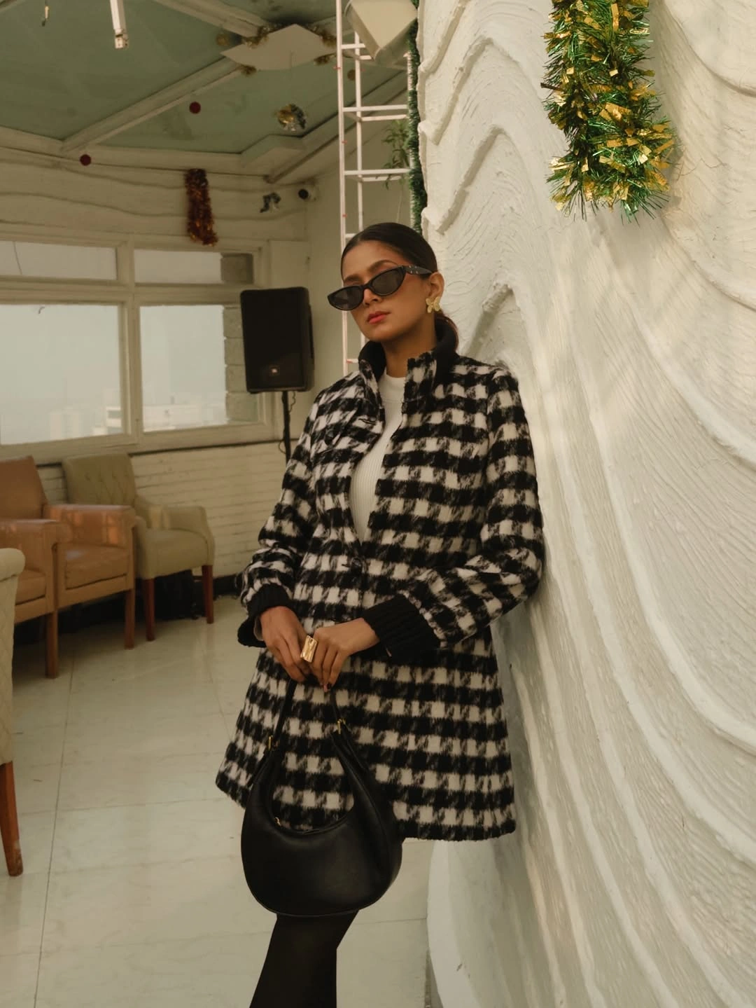 Black-and-cream checked coat with sunglasses and rounded black handbag